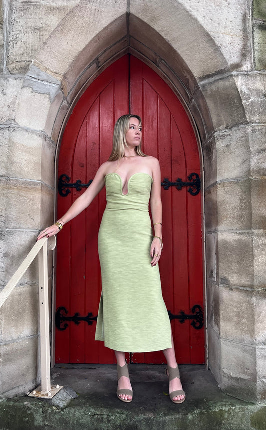 Woman in a green dress standing in front of a red door with stone archway