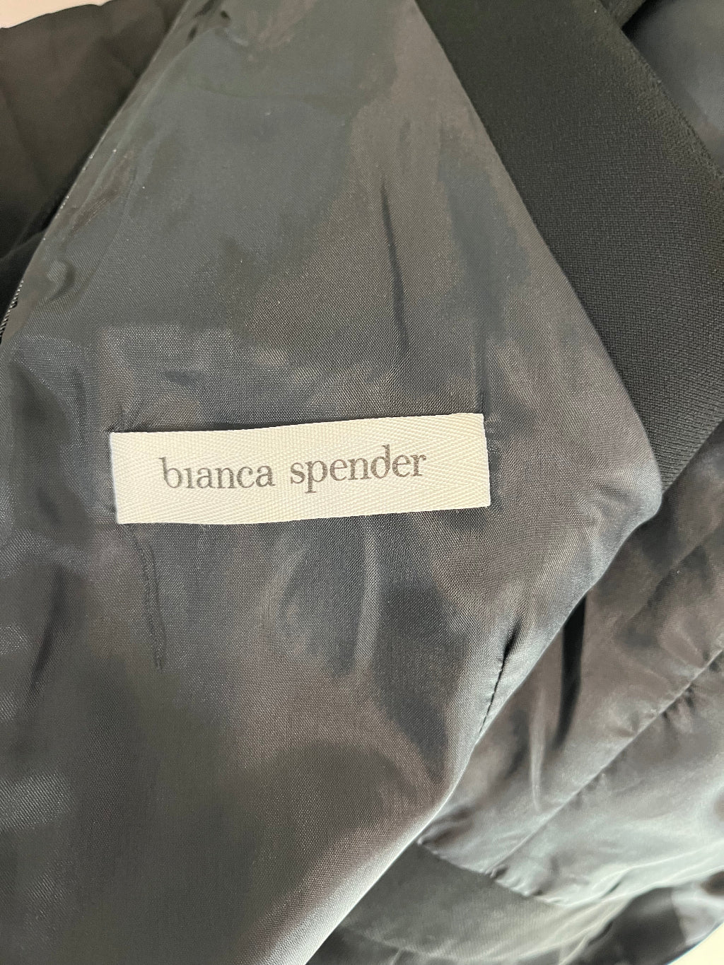 Close-up of a label on a piece of gray fabric with 'bianca spender' branding.