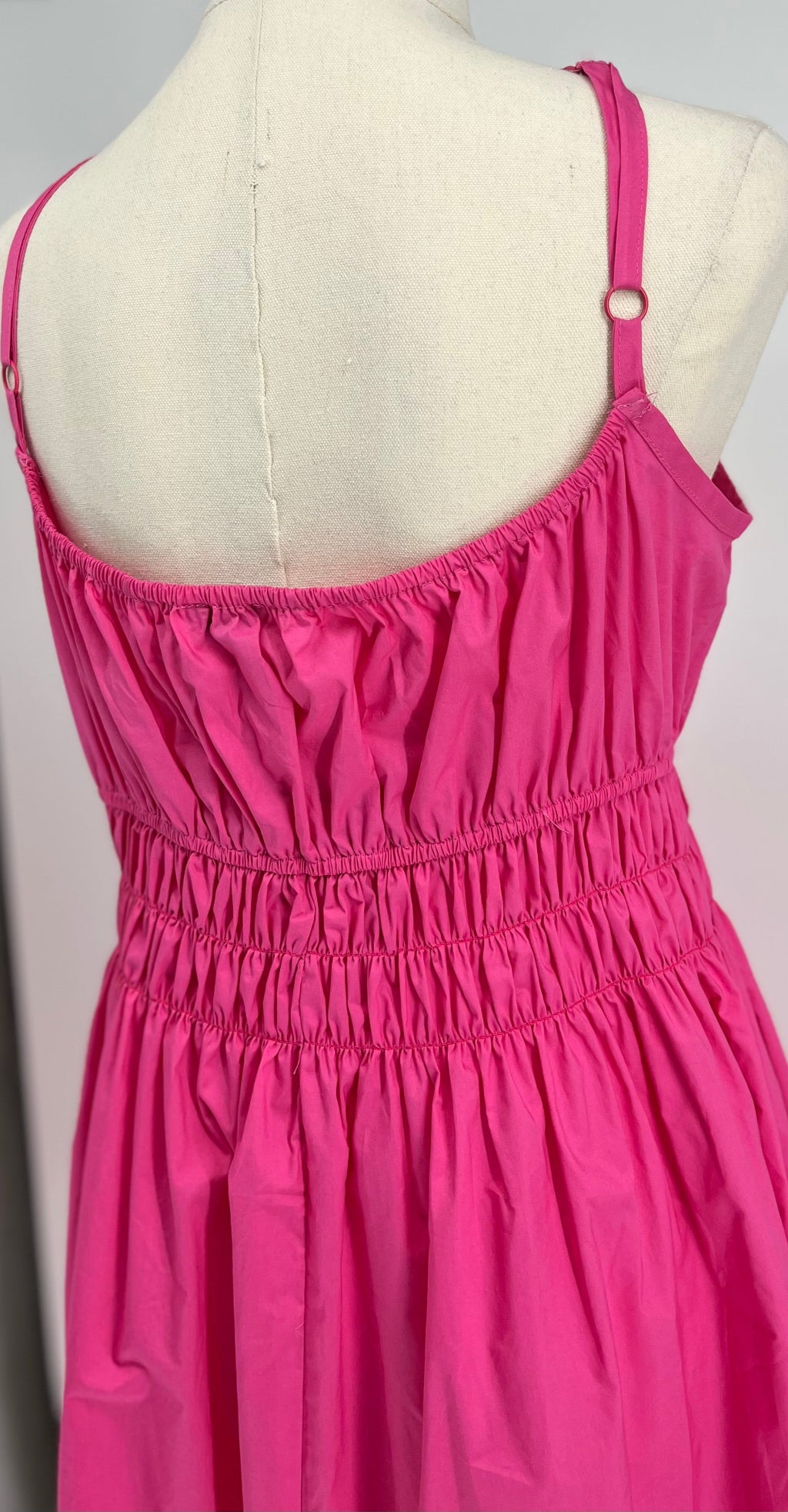Pink dress on a mannequin against a plain background