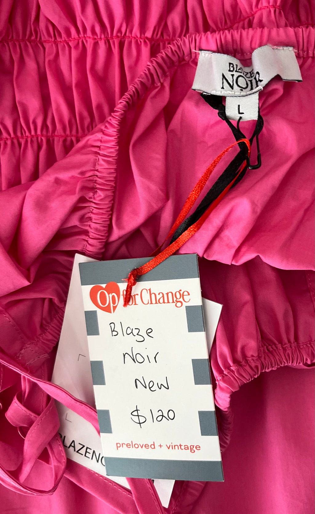 Close-up of a pink garment with a tag from Op for Change on a pink background