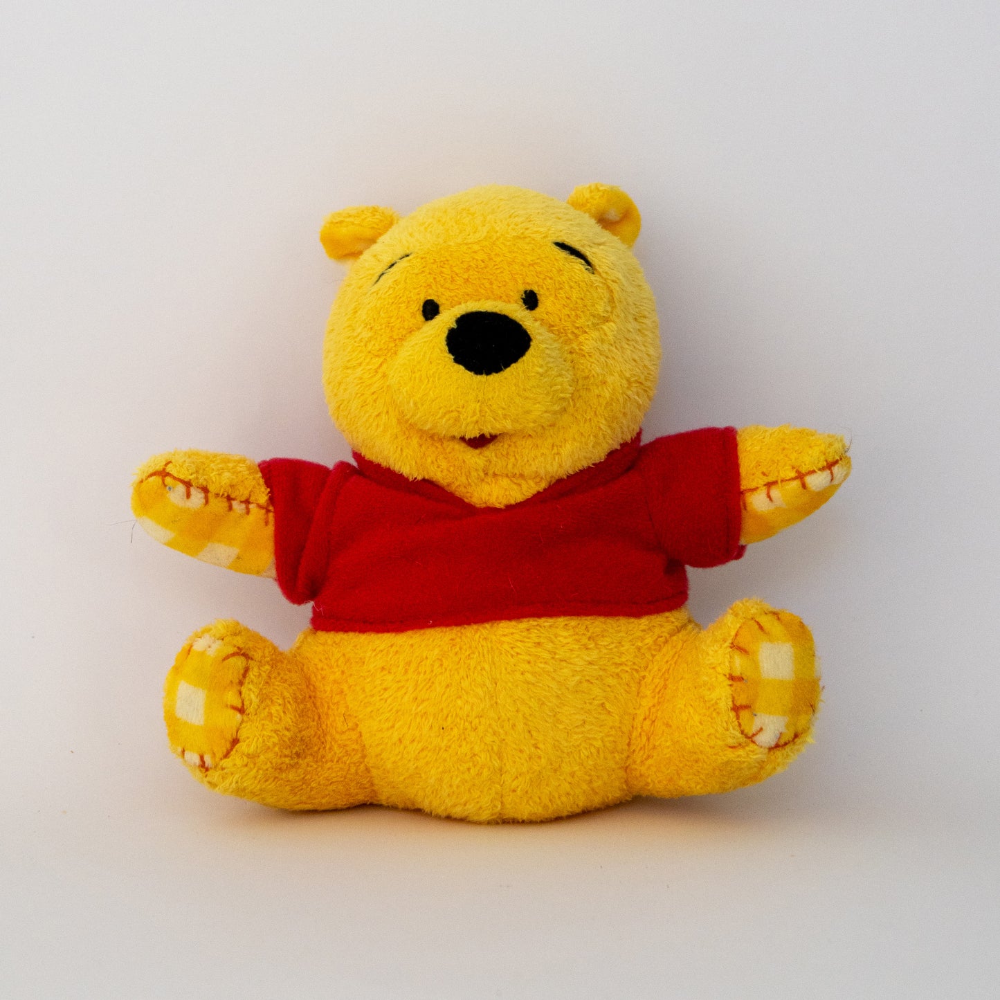 Yellow teddy bear with a red shirt on a white background