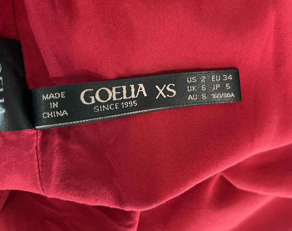 Close-up of a Goelia label on a red garment with size information.