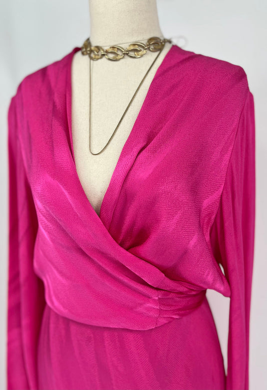 Pink dress on a mannequin with a gold necklace against a white background