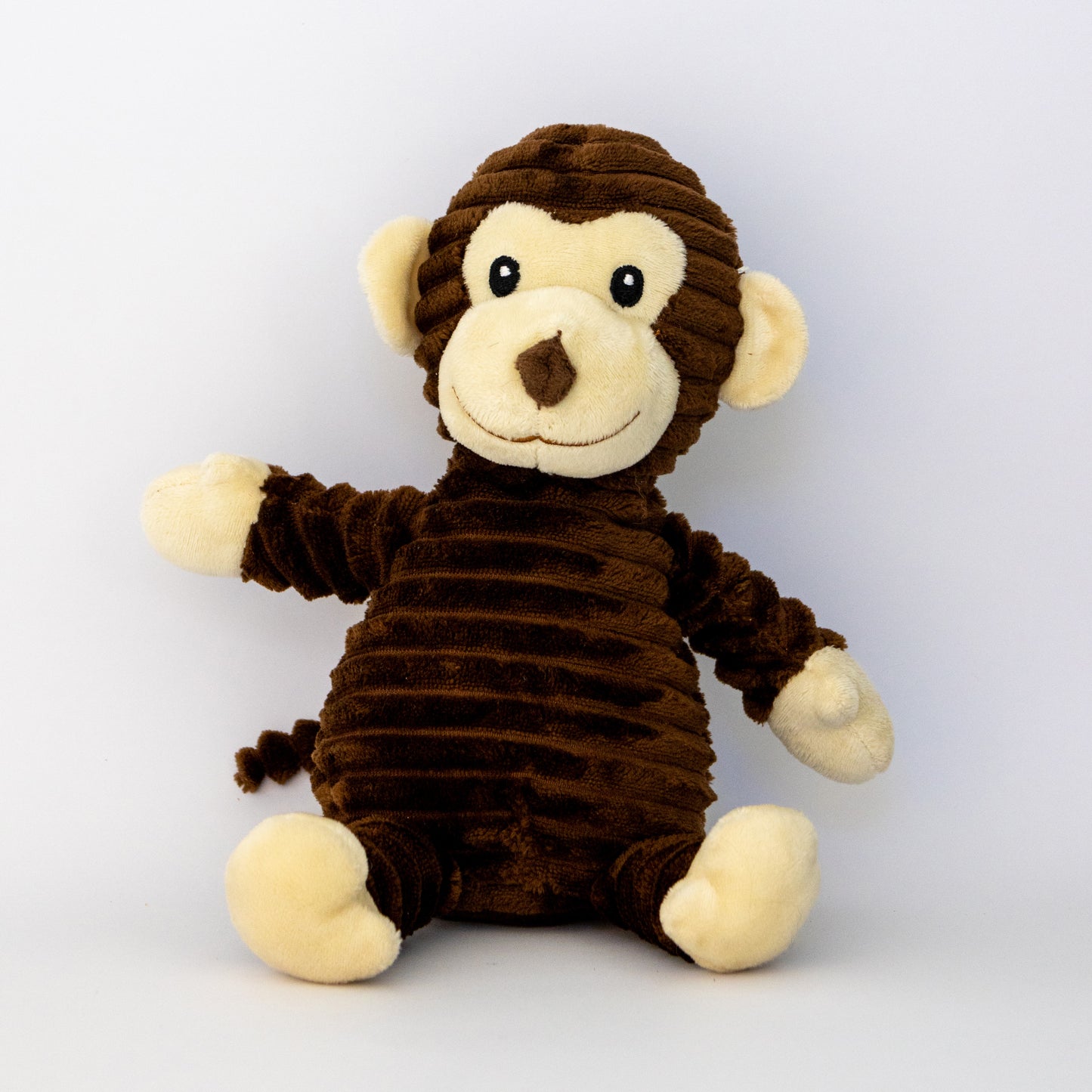 Stuffed monkey toy with brown fur and white face on a light gray background