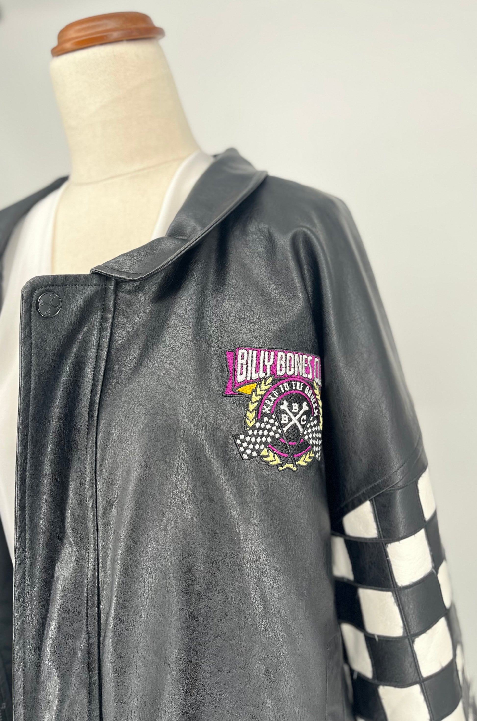 Gray leather jacket with checkered sleeves on a mannequin against a white background