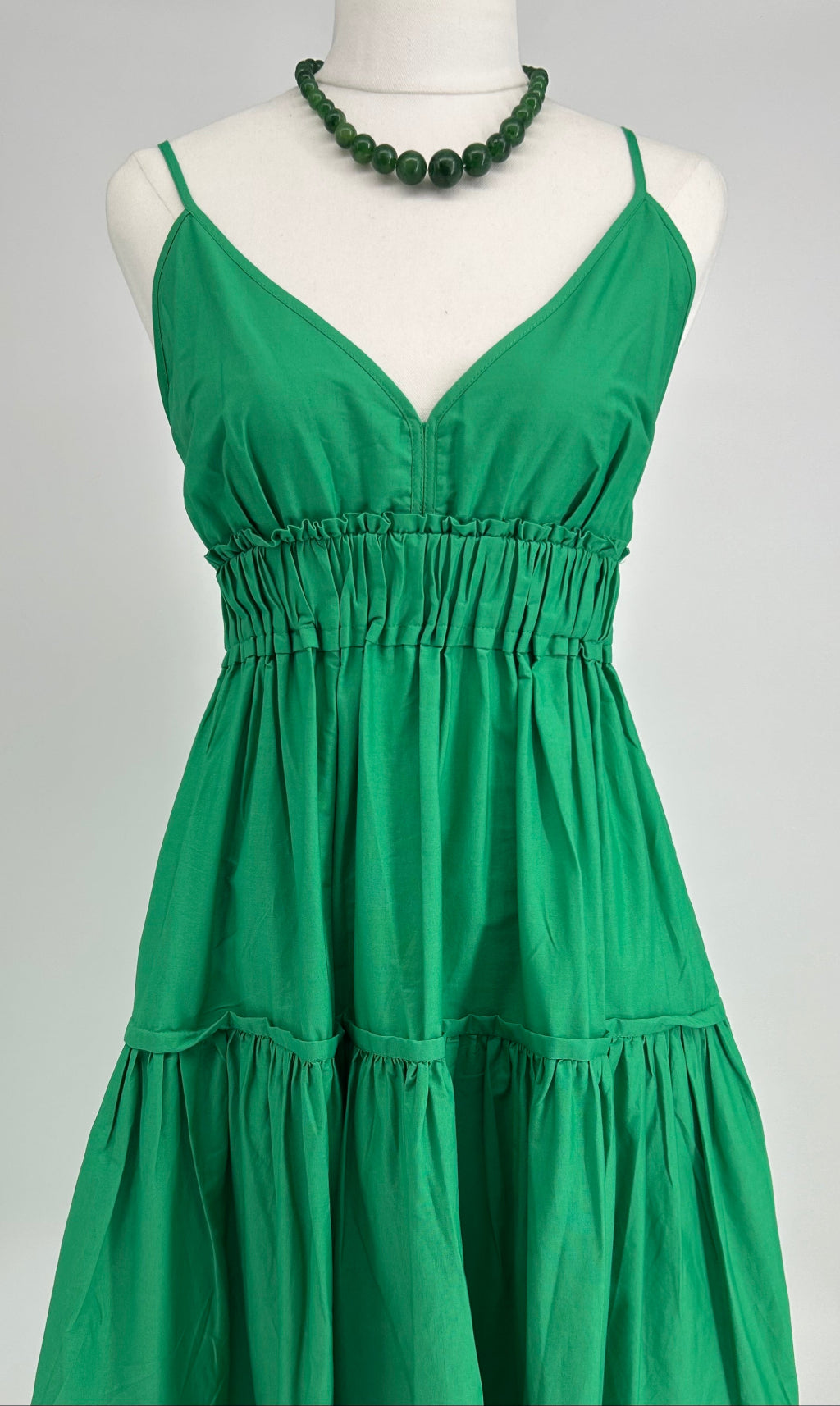 Green dress on a mannequin with a plain background