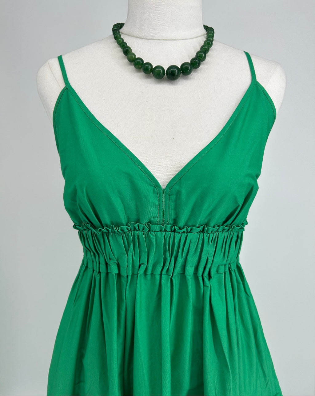 Green dress on a mannequin with a plain background