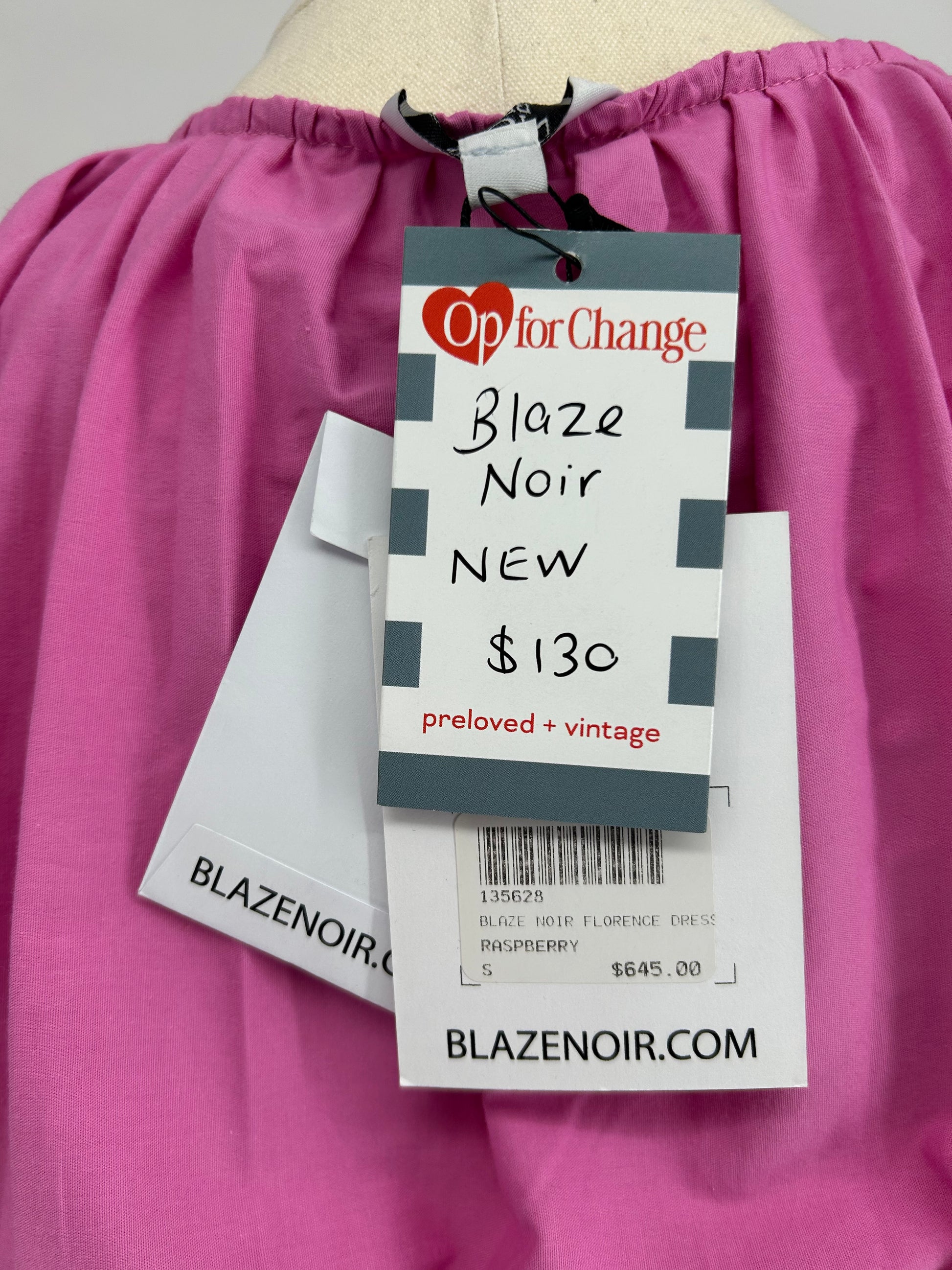 Pink garment with 'Op for Change' and 'Blaze Noir' tags on a pink background