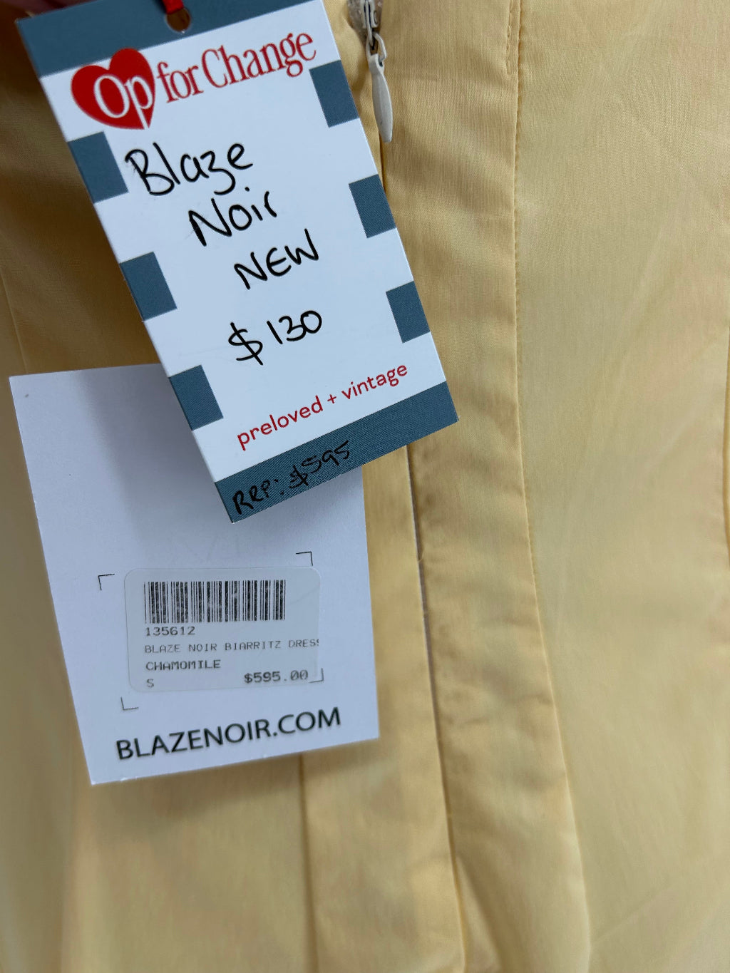 Clothing tag on a yellow garment with 'Op for Change' and 'Blaze Noir' branding.