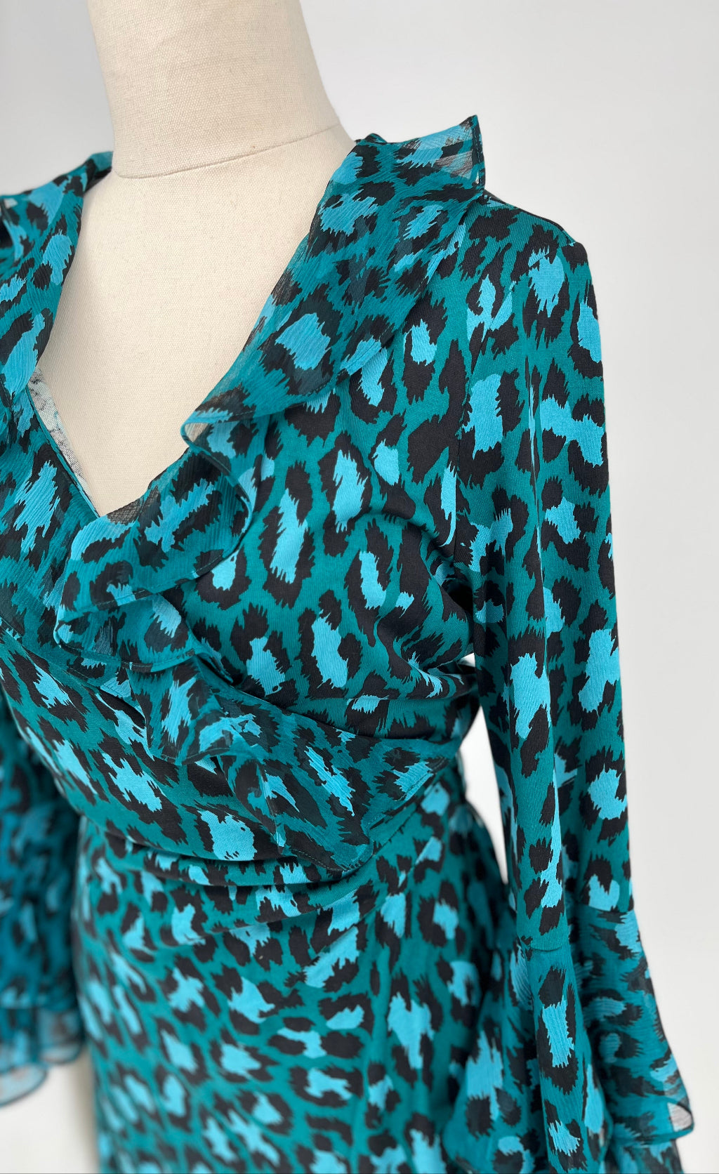 Teal and black leopard print dress on a mannequin against a white background