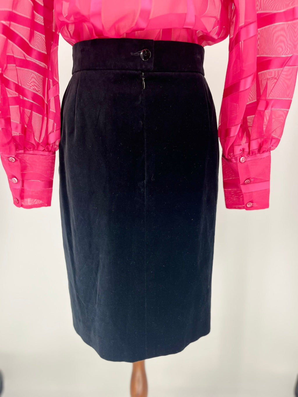 Mannequin wearing a black pencil skirt with a pink sheer blouse.