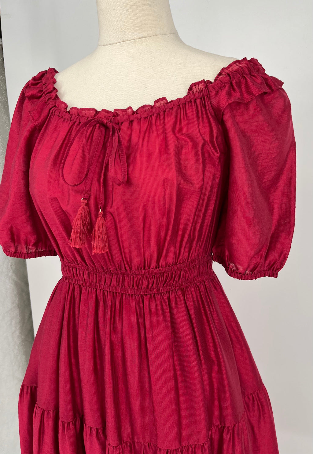 Red dress with puff sleeves on a mannequin against a plain background