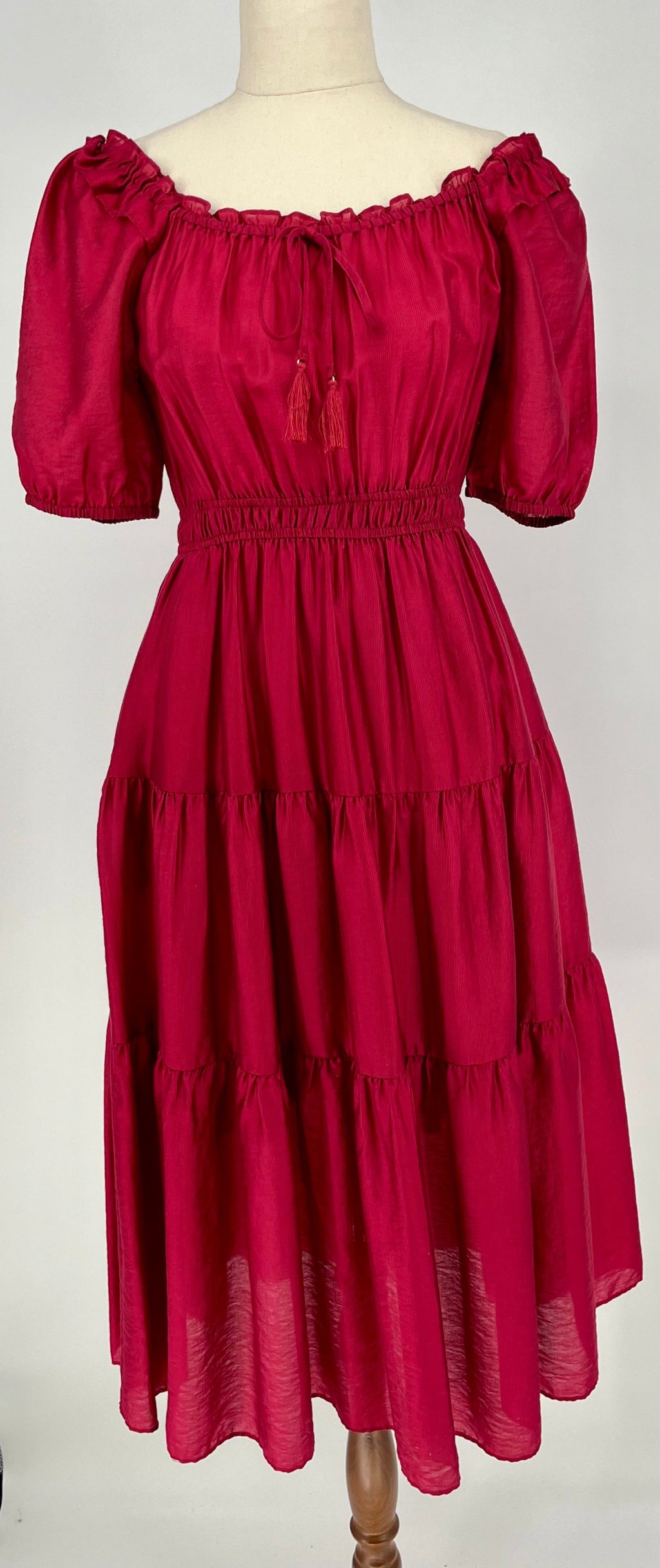 Red dress with puff sleeves on a mannequin against a white background