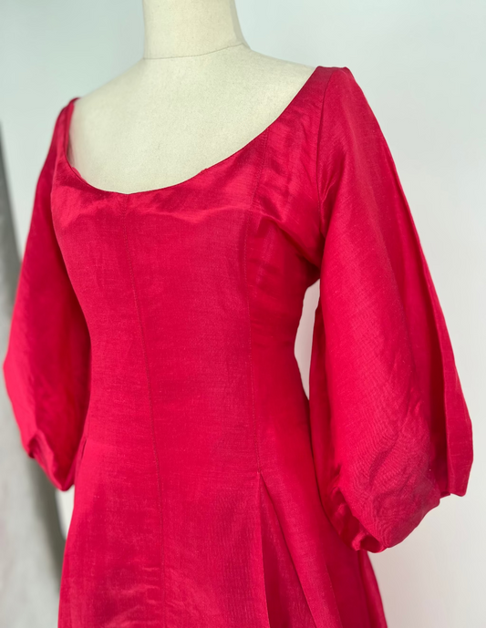 Red dress on a mannequin against a plain background