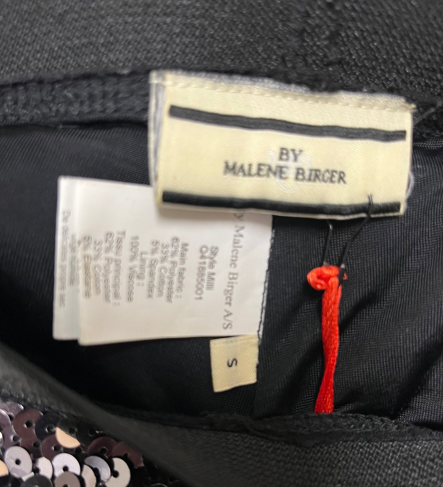 Clothing label with 'By Malene Birger' on a garment with sequin details.