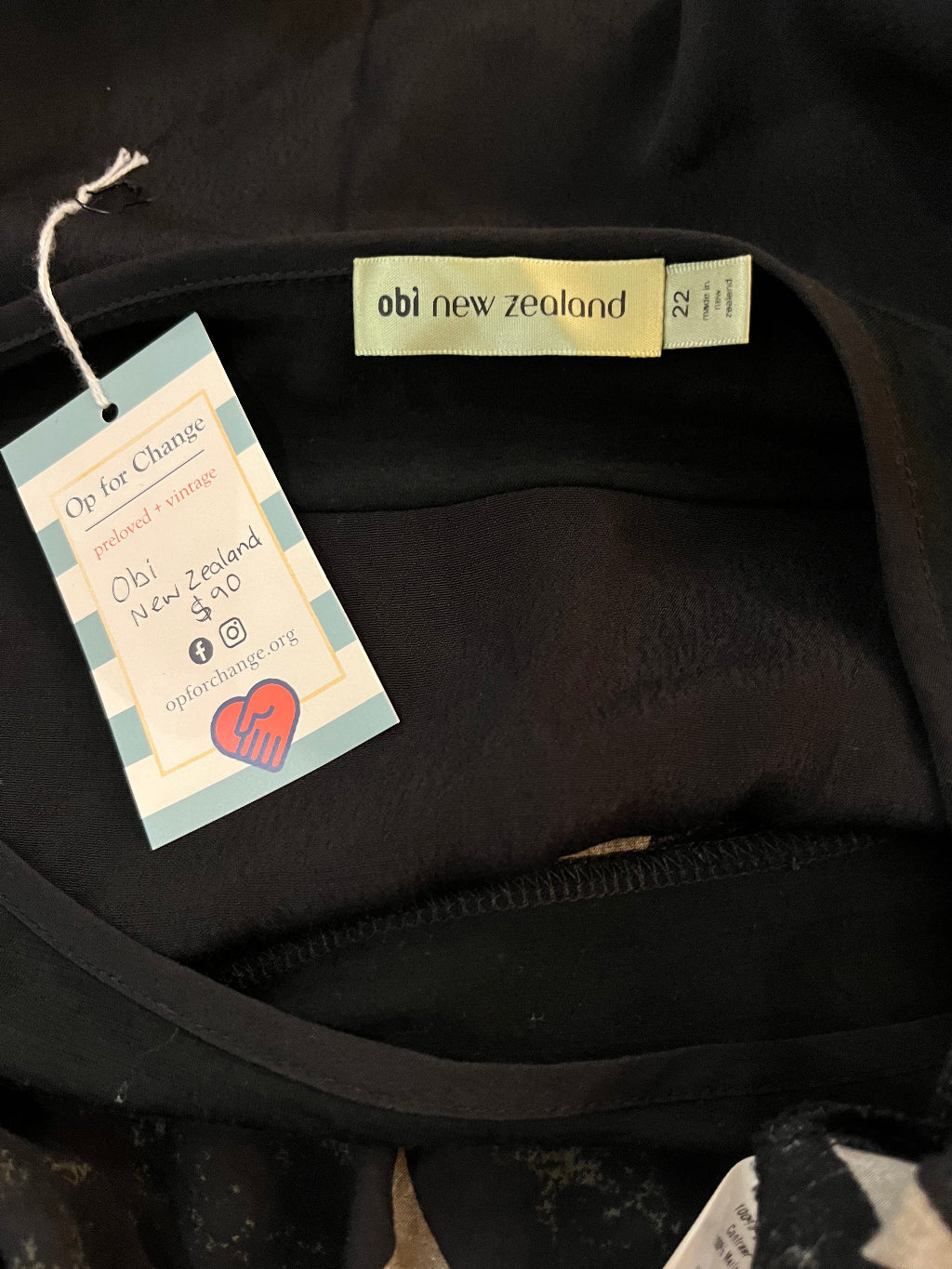 Close-up of a black garment with tags, including a New Zealand label.