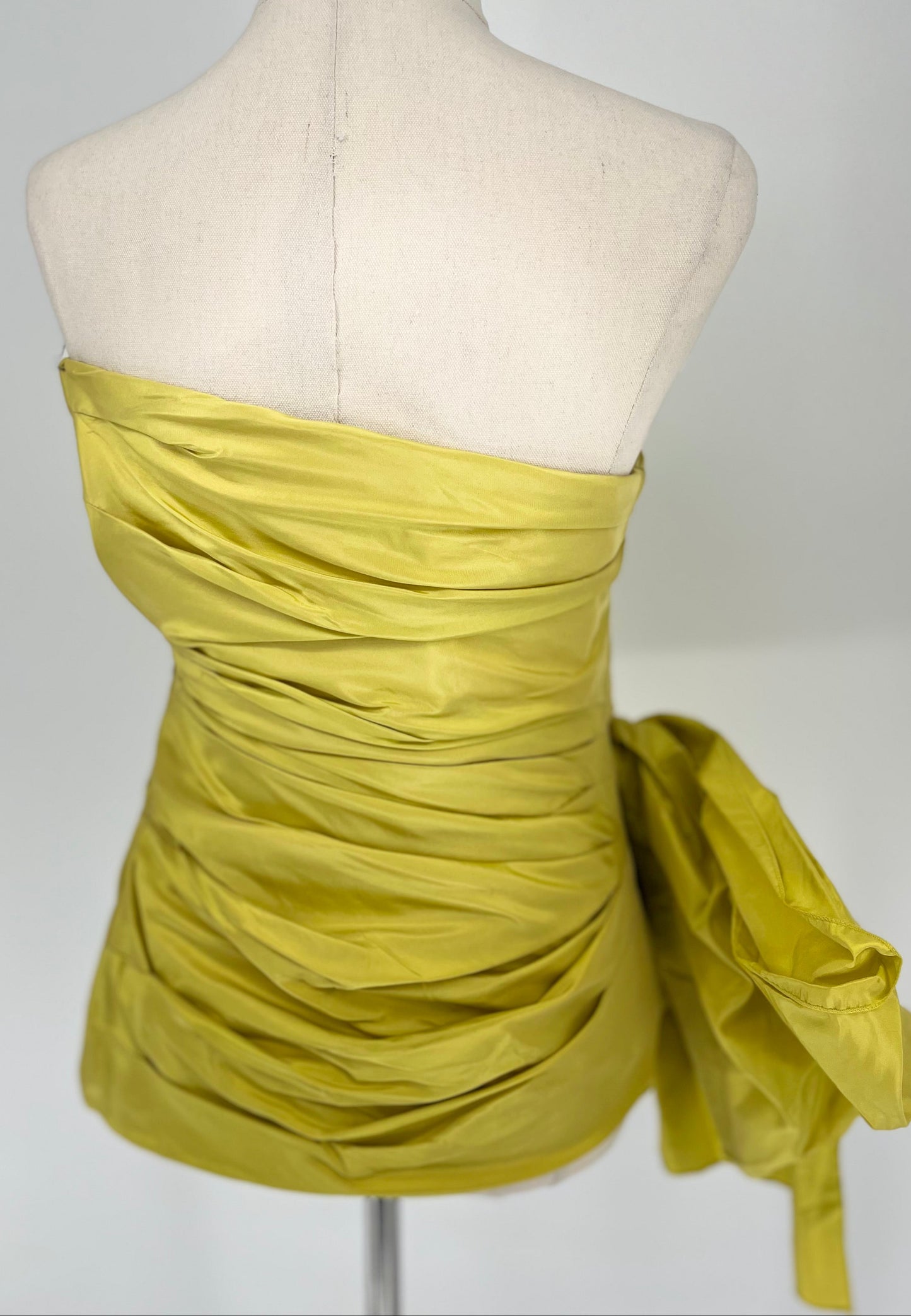Yellow strapless dress on a mannequin against a white background