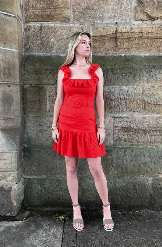 Woman in a red dress standing against a stone wall.