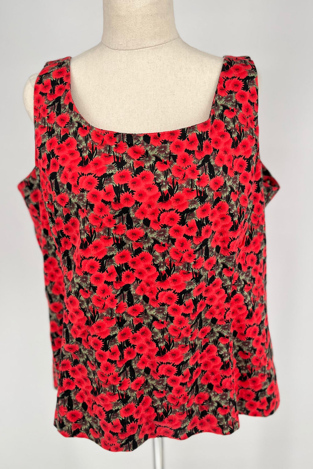 Red floral sleeveless top on a mannequin against a white background