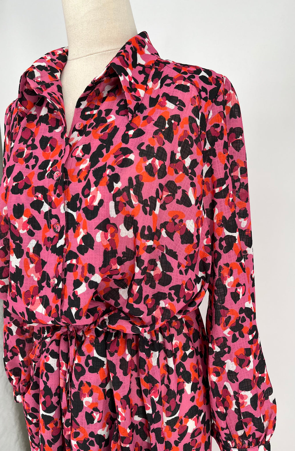 Mannequin wearing a pink and orange leopard print dress against a white background