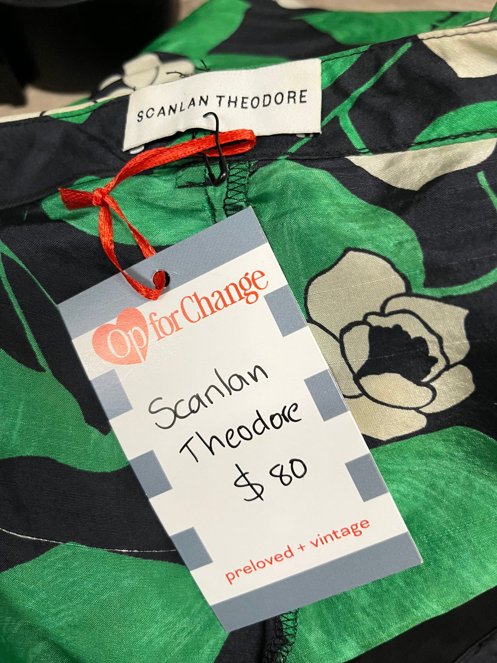 Green floral garment with brand tags on a blurred background