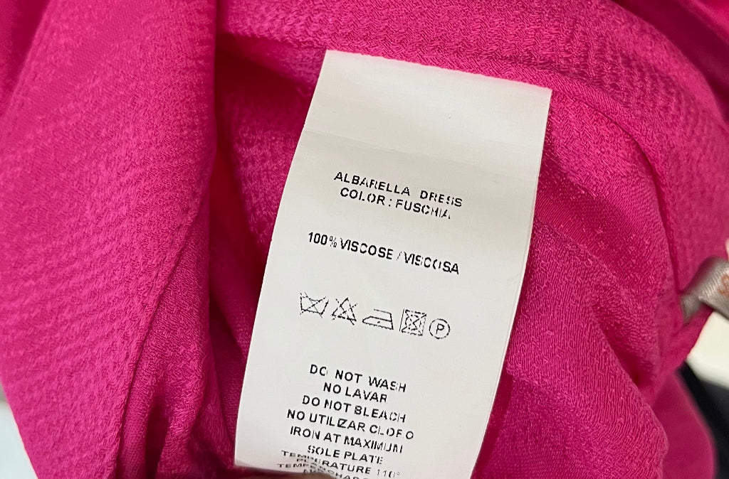 Close-up of a pink garment with a label held by a hand.