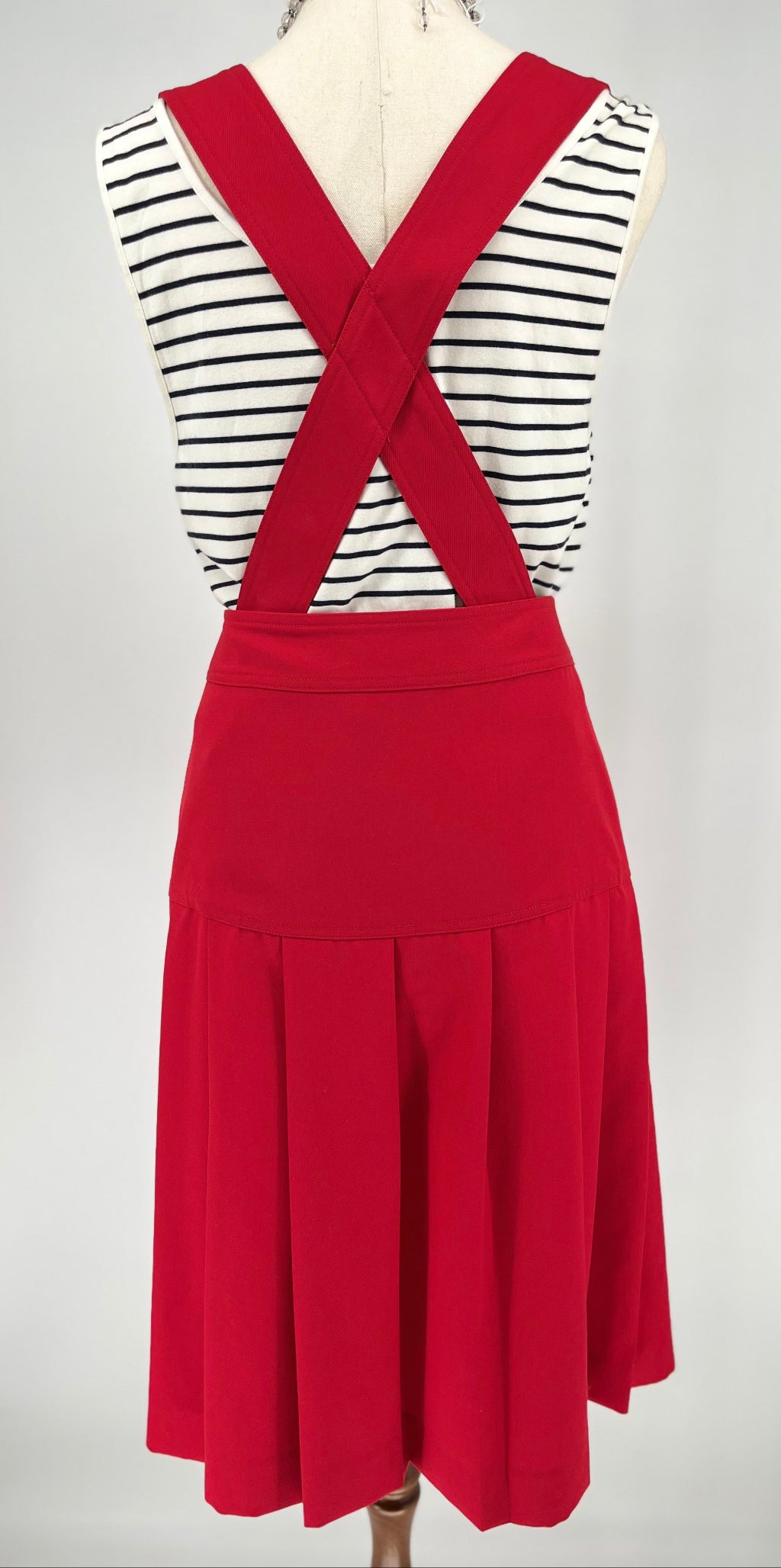 Red dress over a striped shirt on a mannequin against a white background