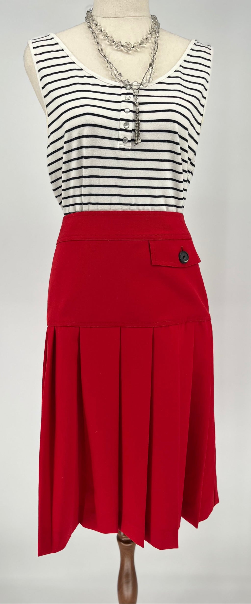 Mannequin wearing a black and white striped top with a red skirt on a plain background