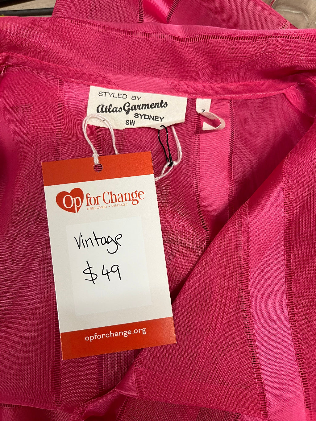Pink jacket with a 'Op for Change' vintage tag on a pink background