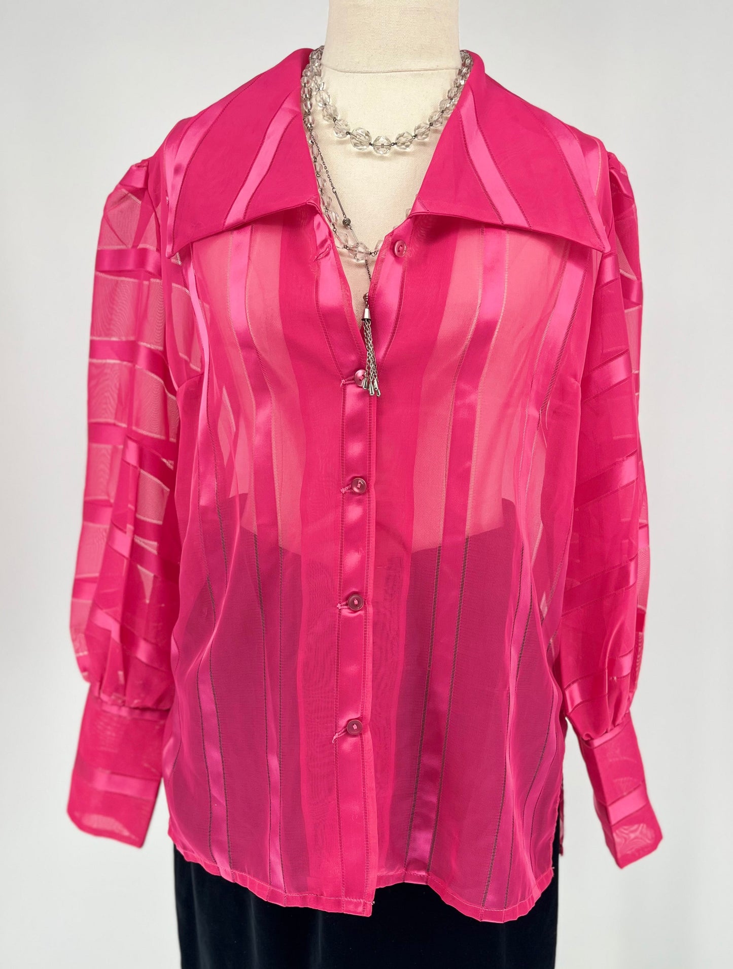 Pink sheer blouse on a mannequin against a white background