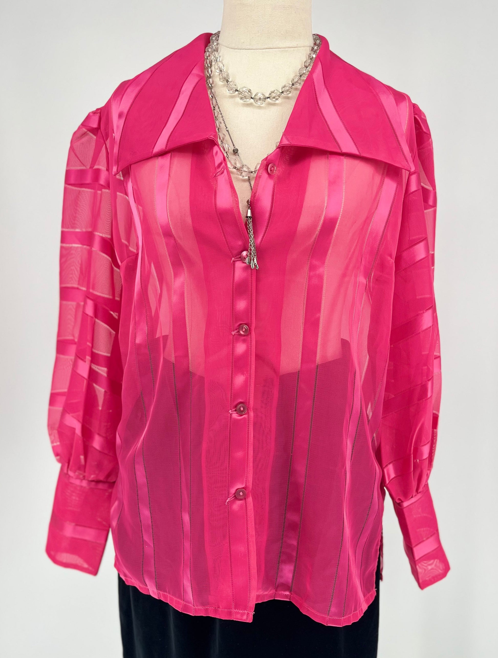 Pink sheer blouse on a mannequin against a white background