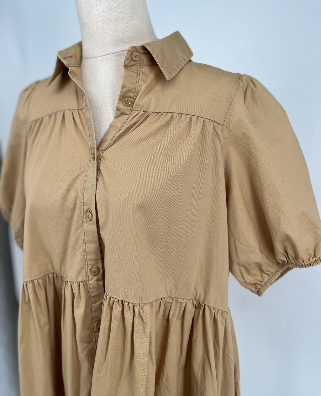 Beige dress on a mannequin against a light blue background