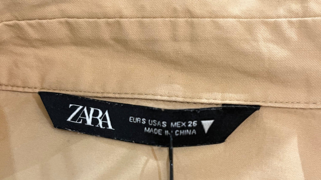 Beige pants with a Zara tag on a wooden hanger