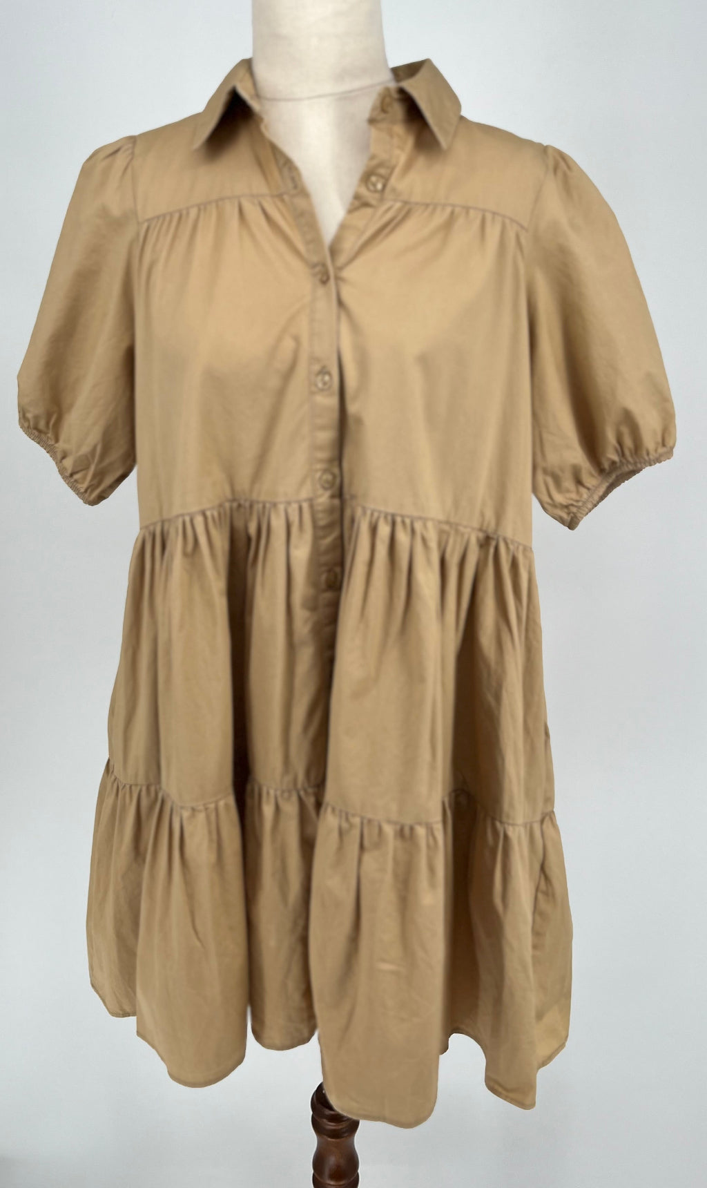 Beige tiered dress on a mannequin against a white background